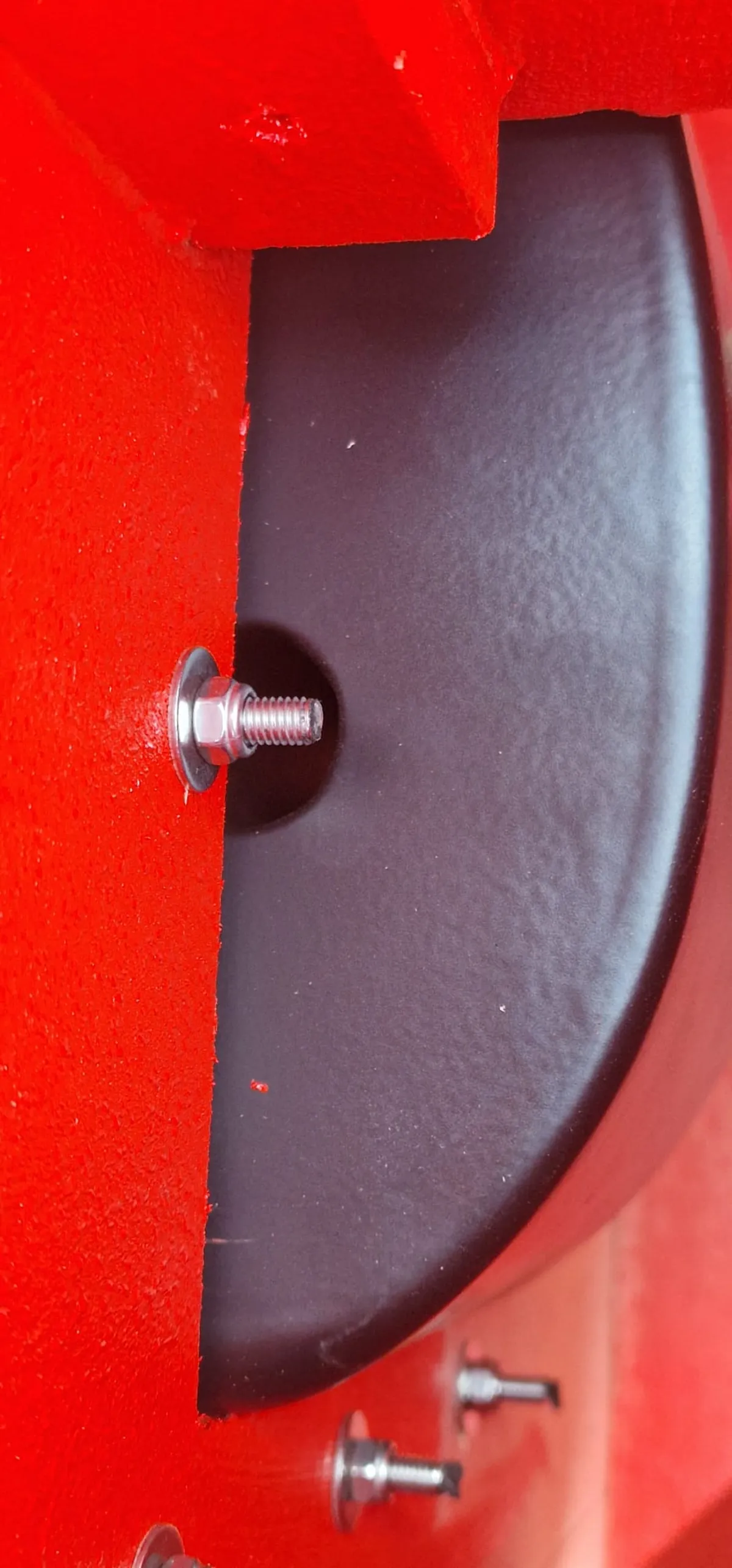 Speaker driver bolted to a red cabinet wall with stainless steel bolts and washers
