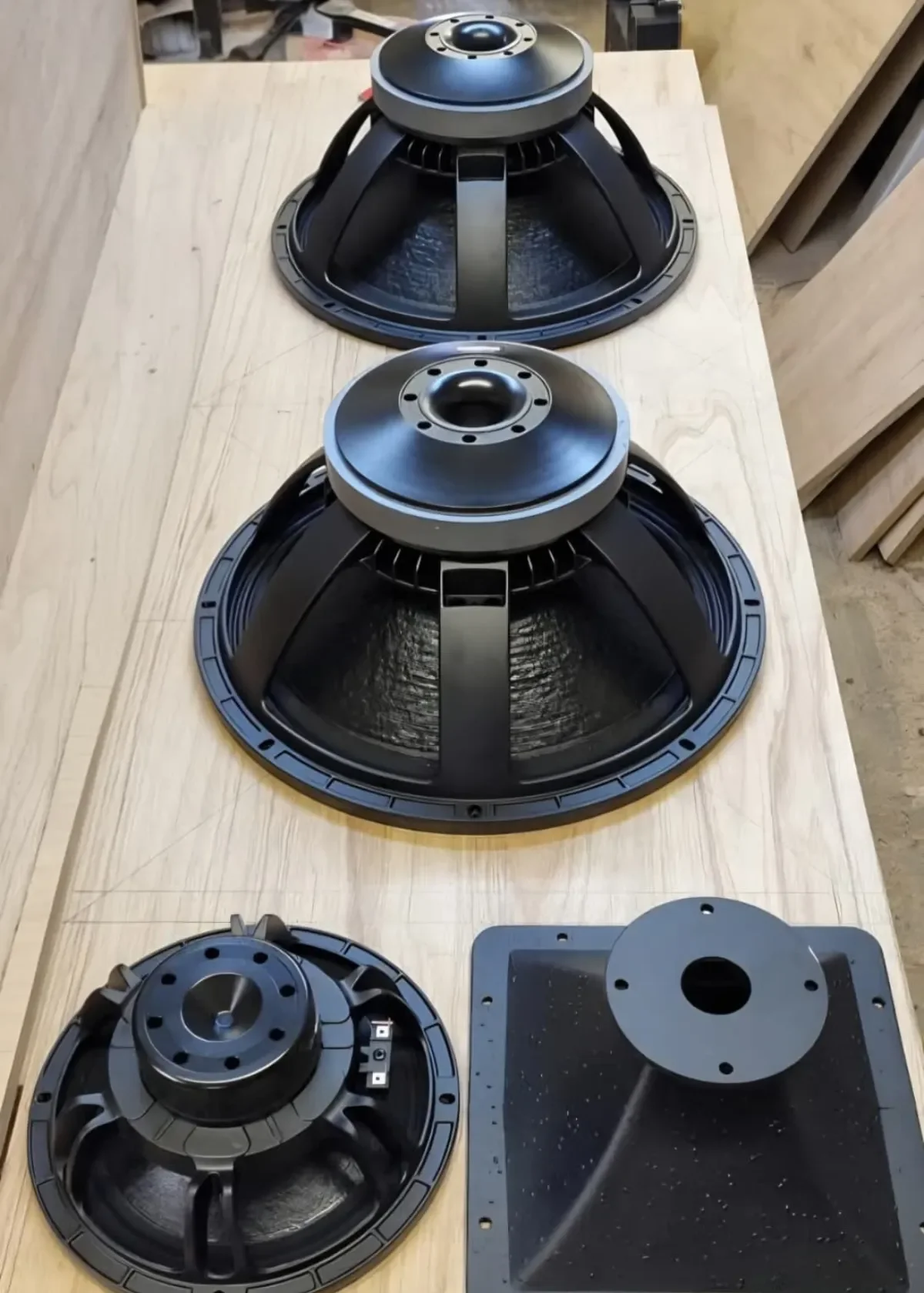 High performance speaker drivers and a horn flare laid out on a plywood workbench