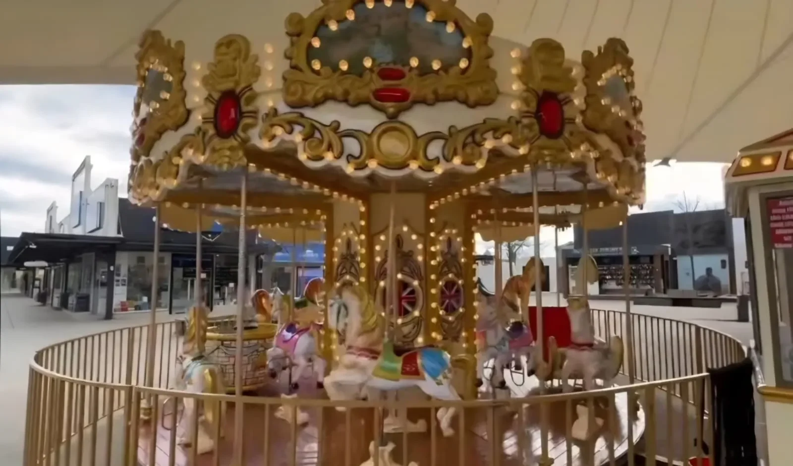 Traditional carousel with ornate golden horses at a covered shopping precinct